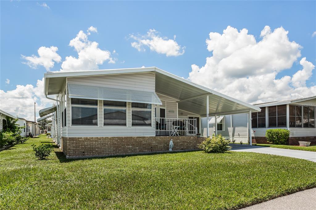 A single-story manufactured home with a brick base, metal siding, and an attached carport — 4332 CHERRYWOOD STREET, WINTER HAVEN, FL