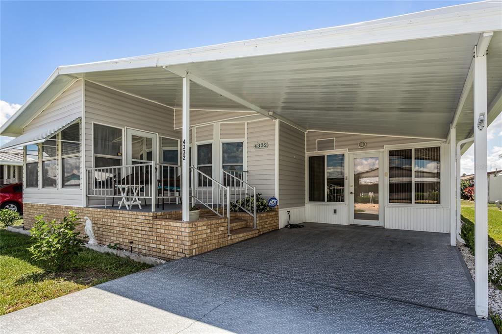 A manufactured home features a brick-based porch, a covered carport, and light gray siding — 4332 CHERRYWOOD STREET, WINTER HAVEN, FL