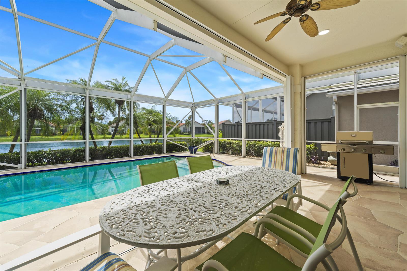 A screened-in patio features a dining set, a swimming pool, and a view of a lake — 637 Masters Way, Palm Beach Gardens FL 33418, PALM BEACH GARDENS, FL