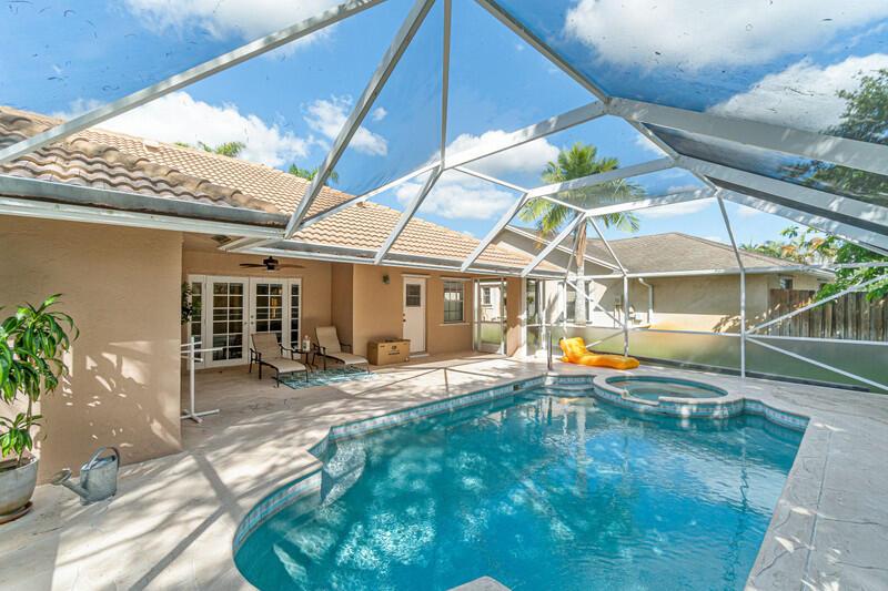 A swimming pool and hot tub are enclosed by a screen cage on a patio — 1840 Hollyhock Road, Wellington FL 33414, WELLINGTON, FL