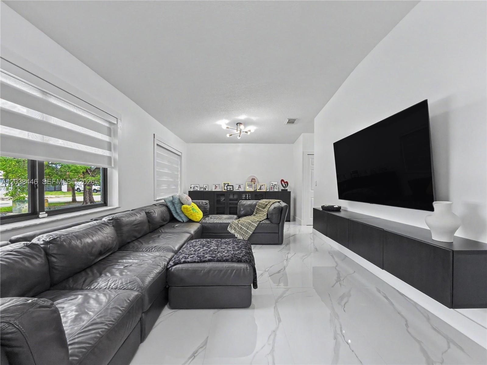 A living room features a large gray sectional, a wall-mounted television, and white marble flooring — 21965 SW 125th Ave, Miami FL 33170, MIAMI, FL