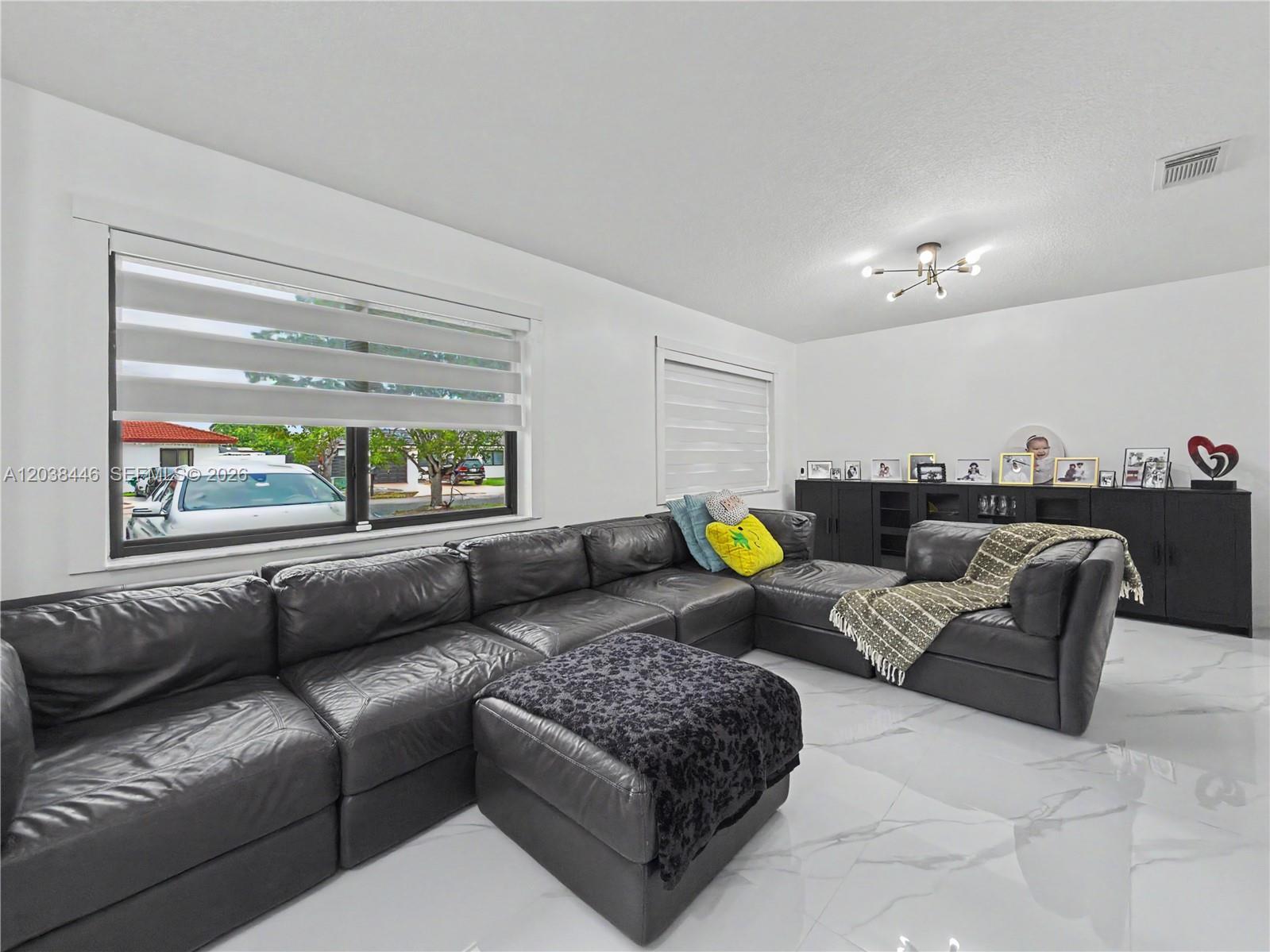A living room features a large black sectional sofa, white marble floors, and a black cabinet — 21965 SW 125th Ave, Miami FL 33170, MIAMI, FL