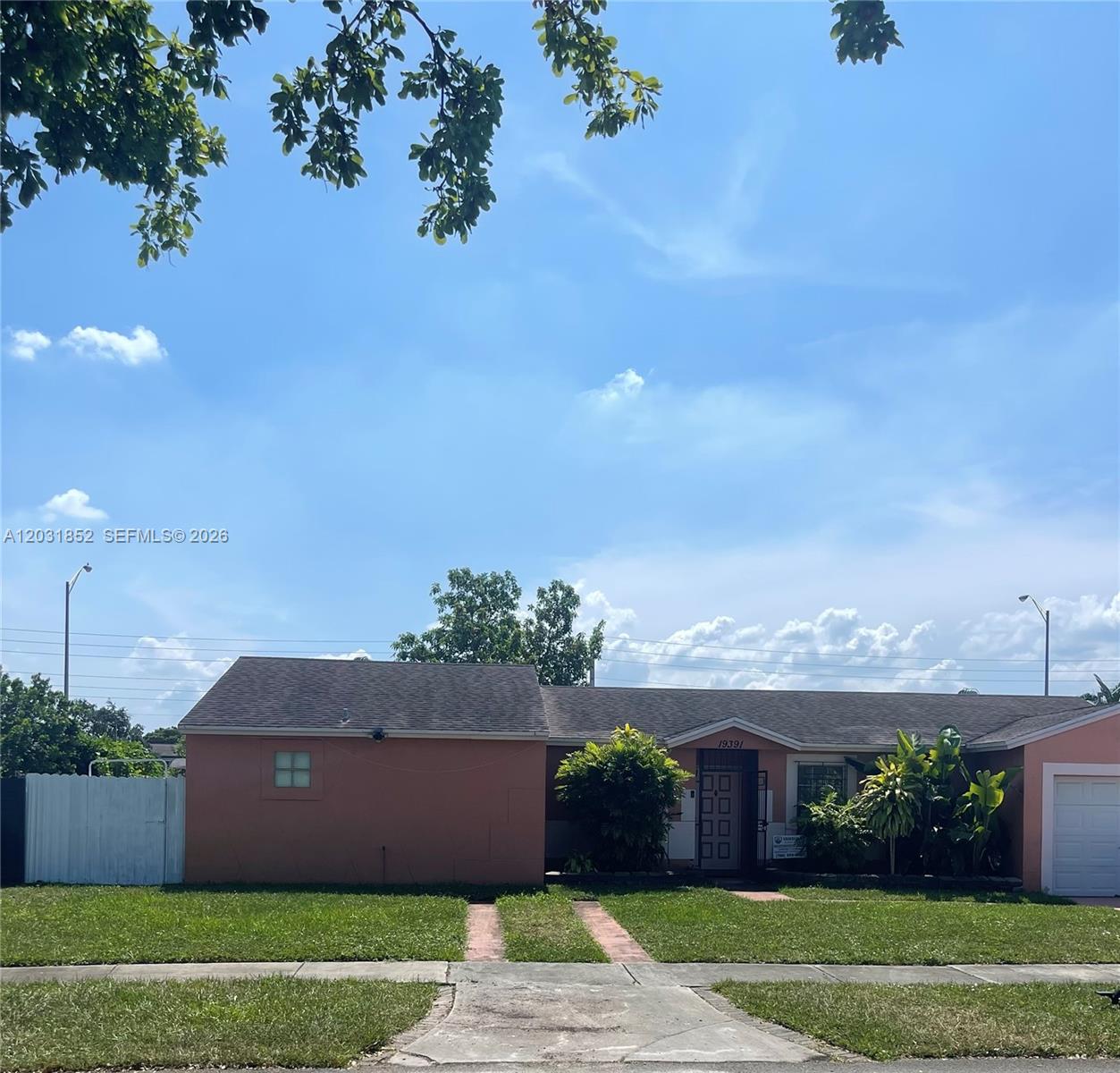 A single-story peach-colored house features a front-facing garage, a lawn, and a paved driveway — 19391 NW 57th Ct, Hialeah FL 33015, HIALEAH, FL