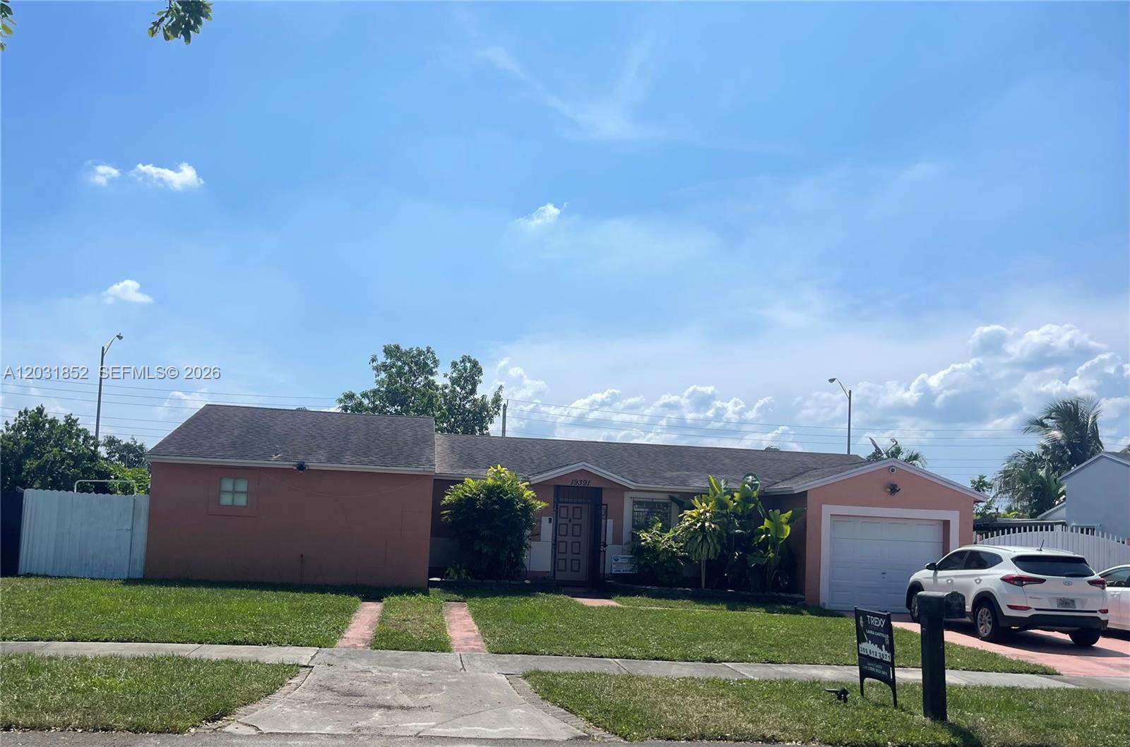 A single-story peach-colored house with a front lawn, driveway, and attached garage — 19391 NW 57th Ct, Hialeah FL 33015, HIALEAH, FL