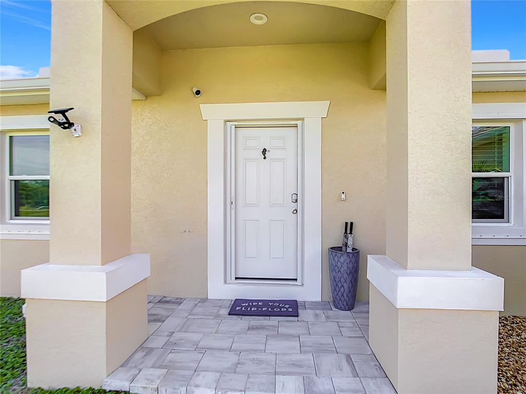 The front entrance features a white door, a tiled porch, and two large support columns — 10024 LEBANON DR, PORT CHARLOTTE, FL