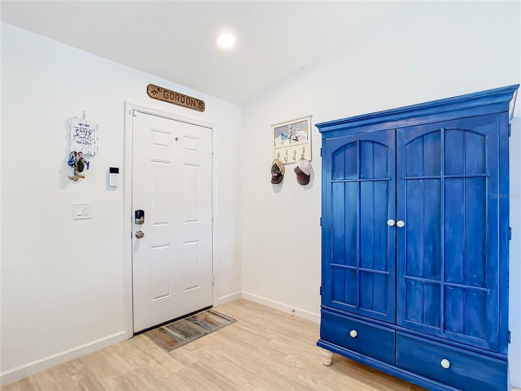 An entryway features a white front door, light wood-look flooring, and a large blue cabinet — 10024 LEBANON DR, PORT CHARLOTTE, FL