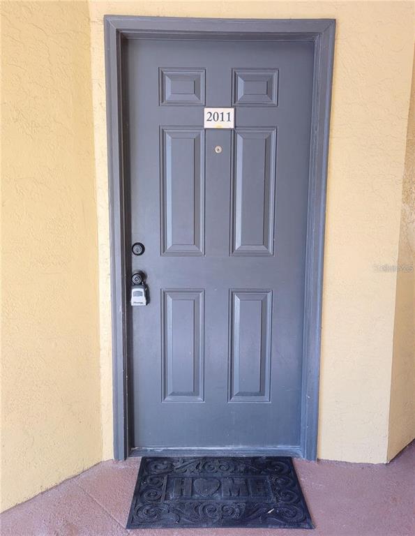A gray front door with the number 2011 and a lockbox sits on a beige wall — 4528 COMMANDER DRIVE UNIT 2011, ORLANDO, FL