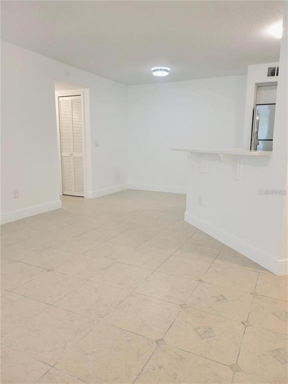 An interior view of a room with white walls, tiled flooring, and a breakfast bar — 4528 COMMANDER DRIVE UNIT 2011, ORLANDO, FL