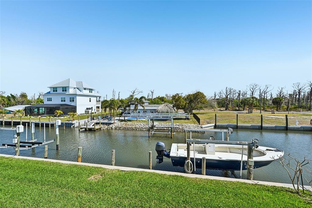 A canal-front property features a multi-story house, a boat lift, and a docked motorboat — 10467 SHERMAN STREET, ENGLEWOOD, FL