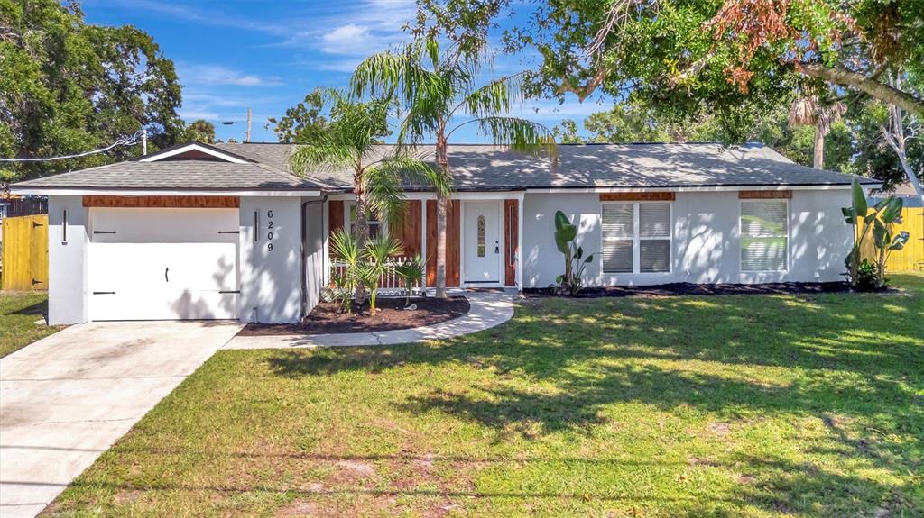 A single-story house with a white garage, gray exterior, and a palm tree in front — 6209 FLAMINGO DRIVE, APOLLO BEACH, FL