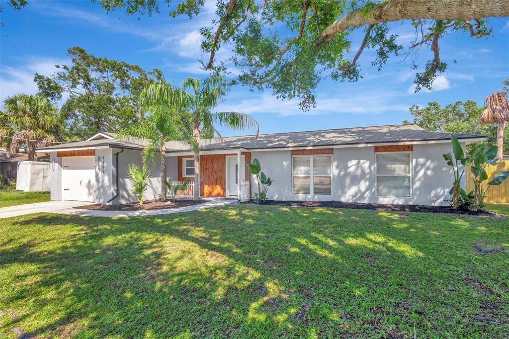 A single-story house with a white exterior, wood-paneled entryway, and a front-facing garage — 6209 FLAMINGO DRIVE, APOLLO BEACH, FL