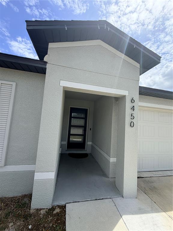 The exterior of a house features a covered entryway, a dark front door, and a garage — 6450 MARINER BOULEVARD, SPRING HILL, FL