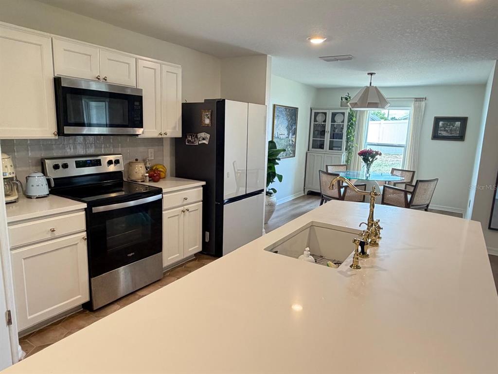 A kitchen features white cabinets, stainless steel appliances, a large island, and an adjacent dining area — 6450 MARINER BOULEVARD, SPRING HILL, FL