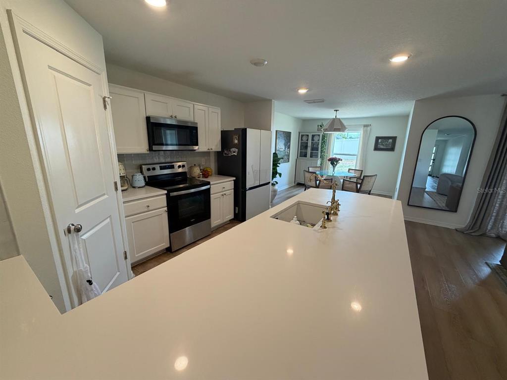 A kitchen features white cabinets, stainless steel appliances, a large island, and light-colored flooring — 6450 MARINER BOULEVARD, SPRING HILL, FL