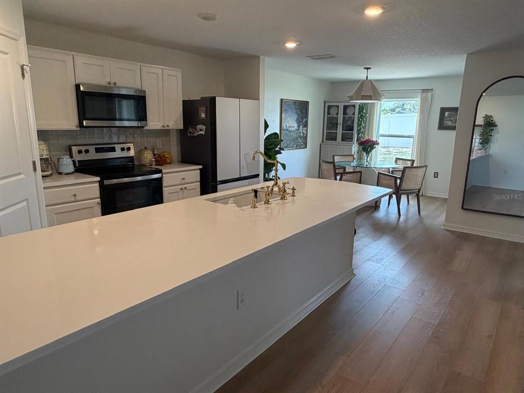 A kitchen features a large white island, stainless steel appliances, and an adjacent dining area — 6450 MARINER BOULEVARD, SPRING HILL, FL