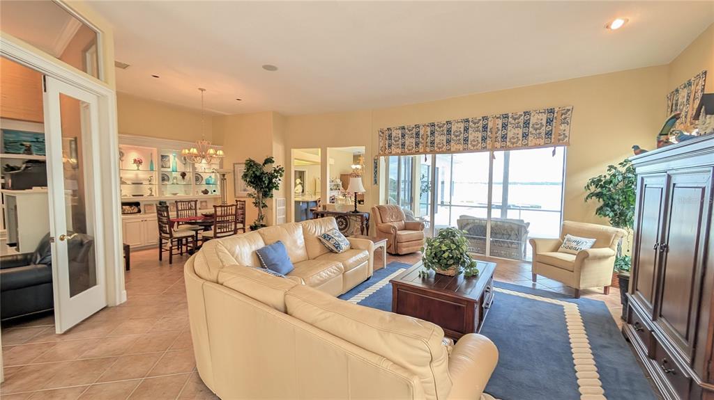 A living room with a beige leather sofa, blue area rug, and sliding glass doors — 4709 DOLPHIN CAY LANE, ST PETERSBURG, FL