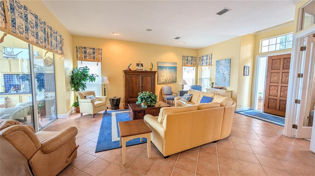 A living room features yellow walls, tile flooring, a blue area rug, and a sectional sofa — 4709 DOLPHIN CAY LANE, ST PETERSBURG, FL