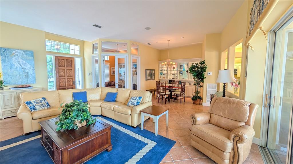A living room features a large beige sectional, a blue area rug, and a dining area — 4709 DOLPHIN CAY LANE, ST PETERSBURG, FL