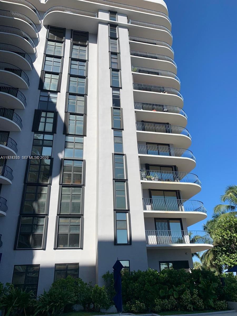 A low-angle exterior view of a white high-rise residential building with curved balconies — 8877 Collins Avenue # 506, Surfside FL 33154, SURFSIDE, FL