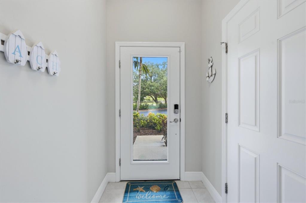An entryway features a white front door with a glass panel, tile flooring, and nautical decor — 10425 PILOTHOUSE COURT UNIT 131, PLACIDA, FL