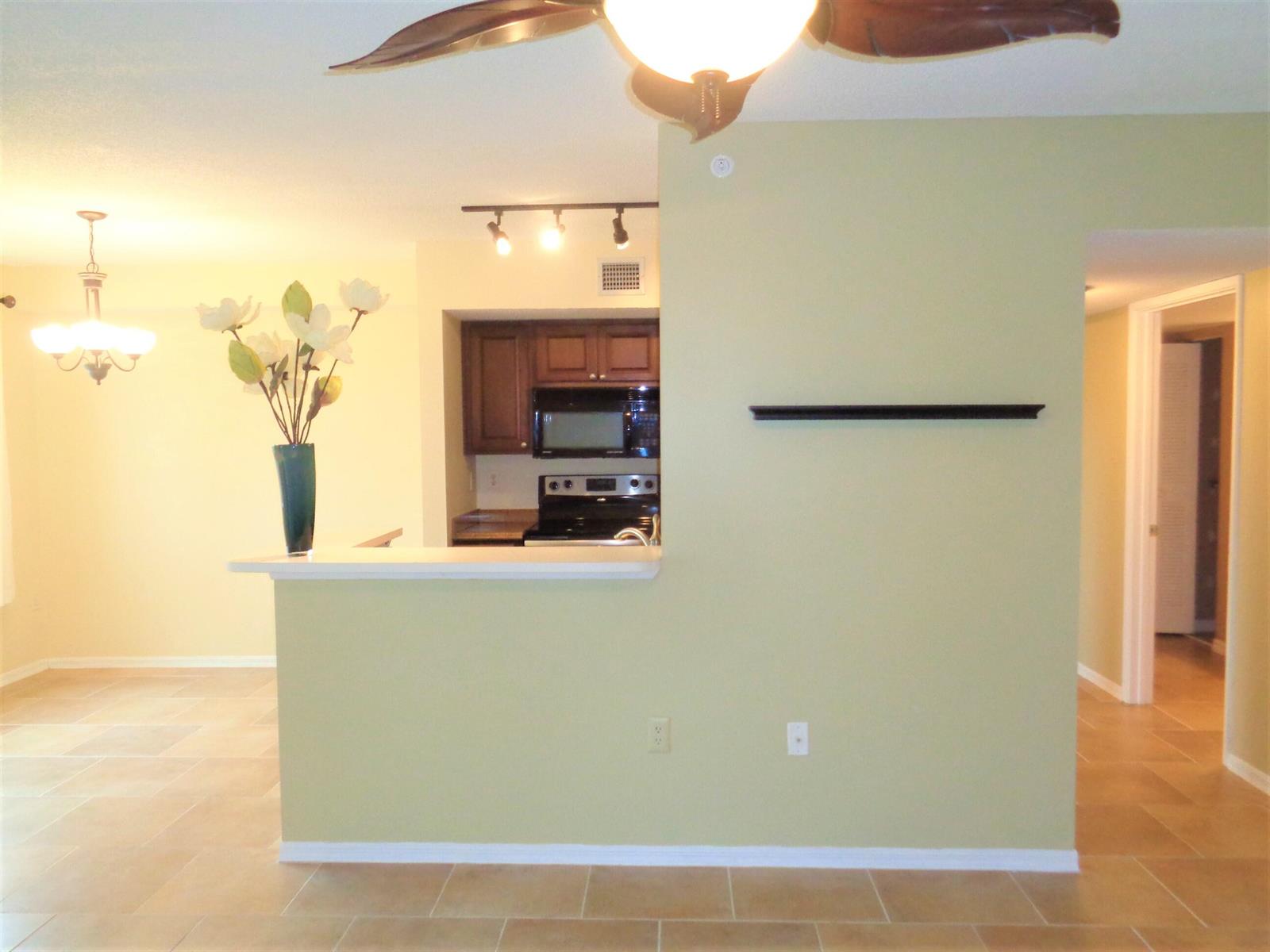 A view of a kitchen with dark cabinets, a breakfast bar, and light-colored tile flooring — 1650 N 42nd Circle # 206, Vero Beach FL 32967, VERO BEACH, FL