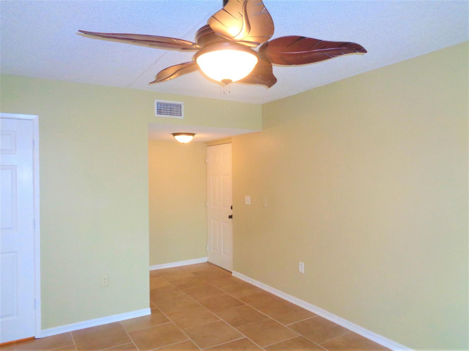 An interior room with light green walls, tile flooring, and a tropical-style ceiling fan — 1650 N 42nd Circle # 206, Vero Beach FL 32967, VERO BEACH, FL