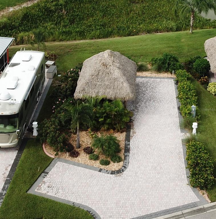 An aerial view shows a paved driveway, a thatched-roof tiki hut, and a parked motorhome — 3258 RED TAIL HAWK DRIVE, POLK CITY, FL