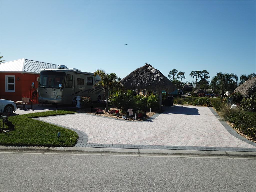 A paved driveway features a tiki hut and a parked recreational vehicle next to a house — 3258 RED TAIL HAWK DRIVE, POLK CITY, FL