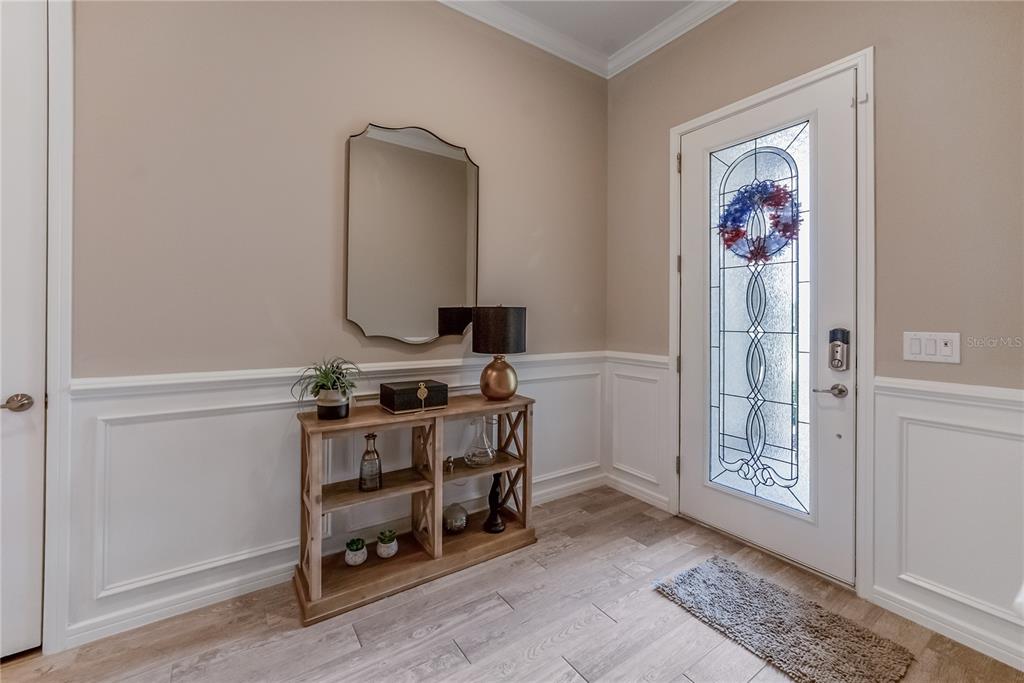An entryway features wood-look tile flooring, white wainscoting, a console table, and a glass-paneled door — 9125 SW 57TH PLACE ROAD, OCALA, FL