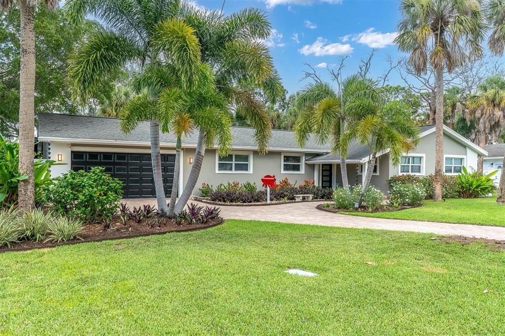 A single-story house with a gray exterior, a paved driveway, and palm trees in the yard — 1625 NORTH DAKOTA AVENUE NE, ST PETERSBURG, FL