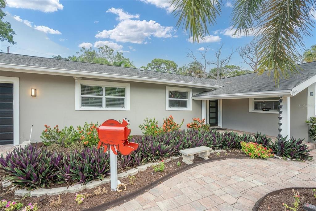 A single-story house exterior features a crab-shaped mailbox, stone walkway, and purple landscaping plants — 1625 NORTH DAKOTA AVENUE NE, ST PETERSBURG, FL