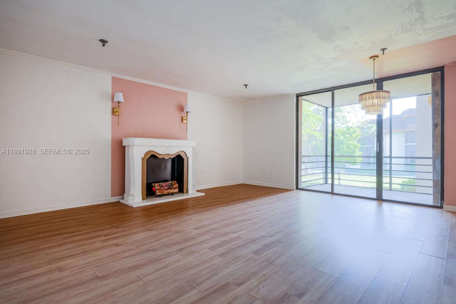 A living room features wood-look flooring, a white fireplace, pink accent wall, and sliding doors — 665 NE 195th St # 222, Miami FL 33179, MIAMI, FL