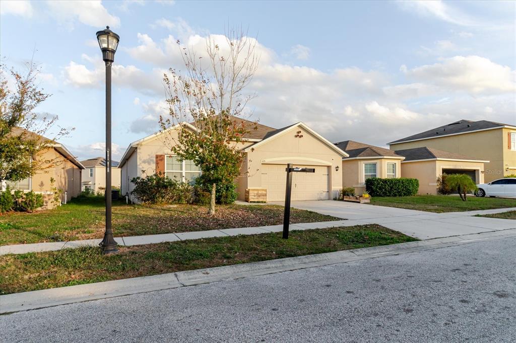 A single-story suburban house with a beige exterior, a two-car garage, and a front lawn — 525 SQUIRES GROVE DRIVE, WINTER HAVEN, FL
