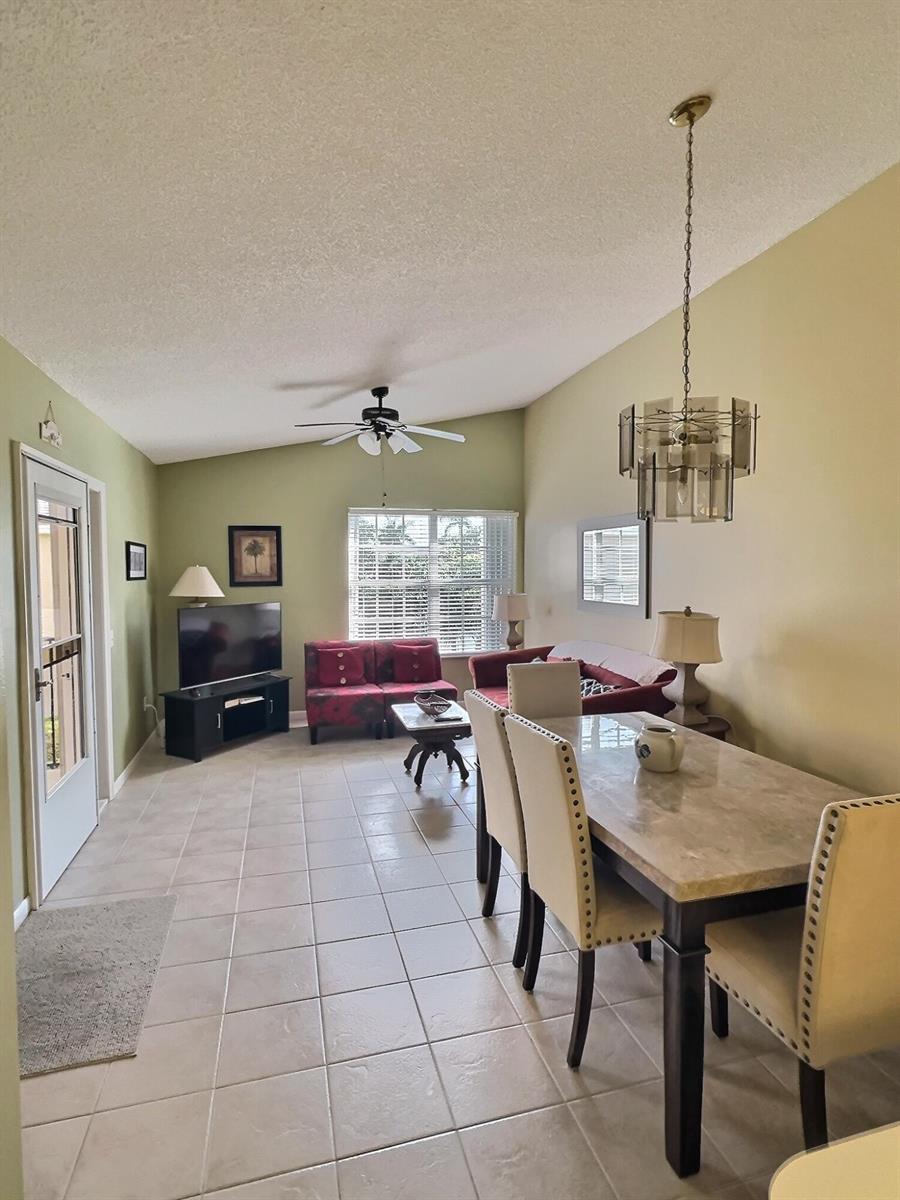 A combined living and dining area features tile flooring, a vaulted ceiling, and neutral walls — 117 Waterside Drive # 117, Hypoluxo FL 33462, HYPOLUXO, FL