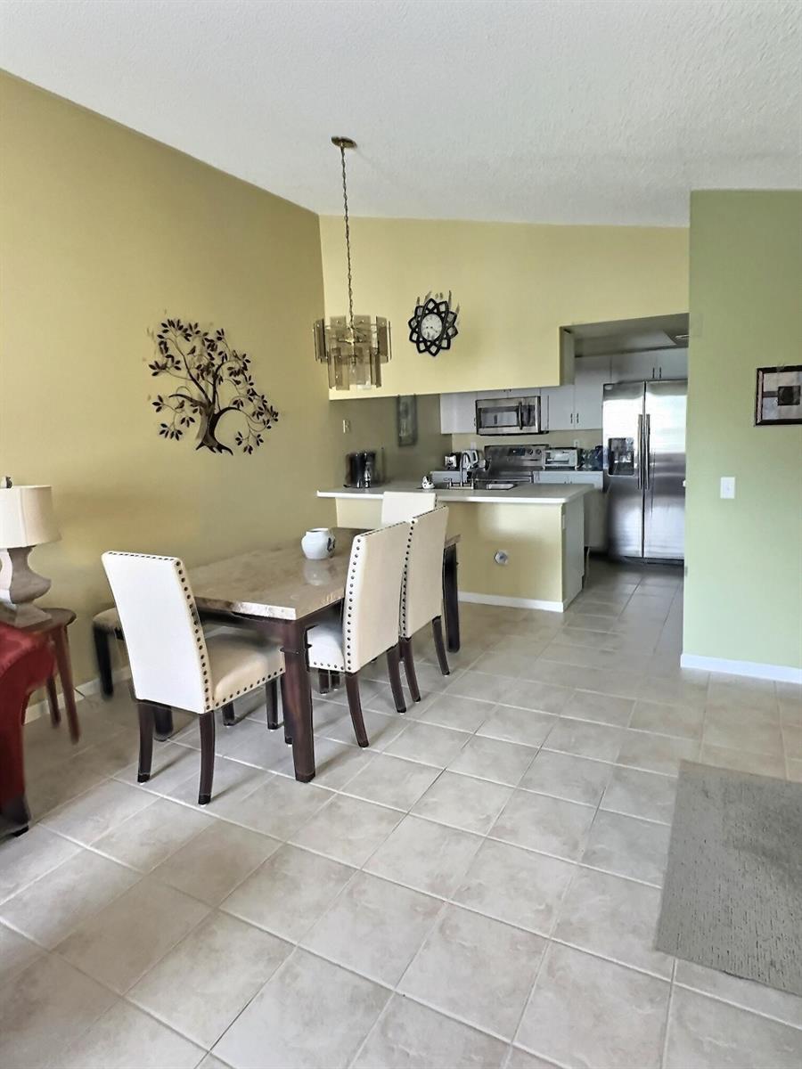 A dining area with a stone-topped table and chairs sits adjacent to an open kitchen — 117 Waterside Drive # 117, Hypoluxo FL 33462, HYPOLUXO, FL