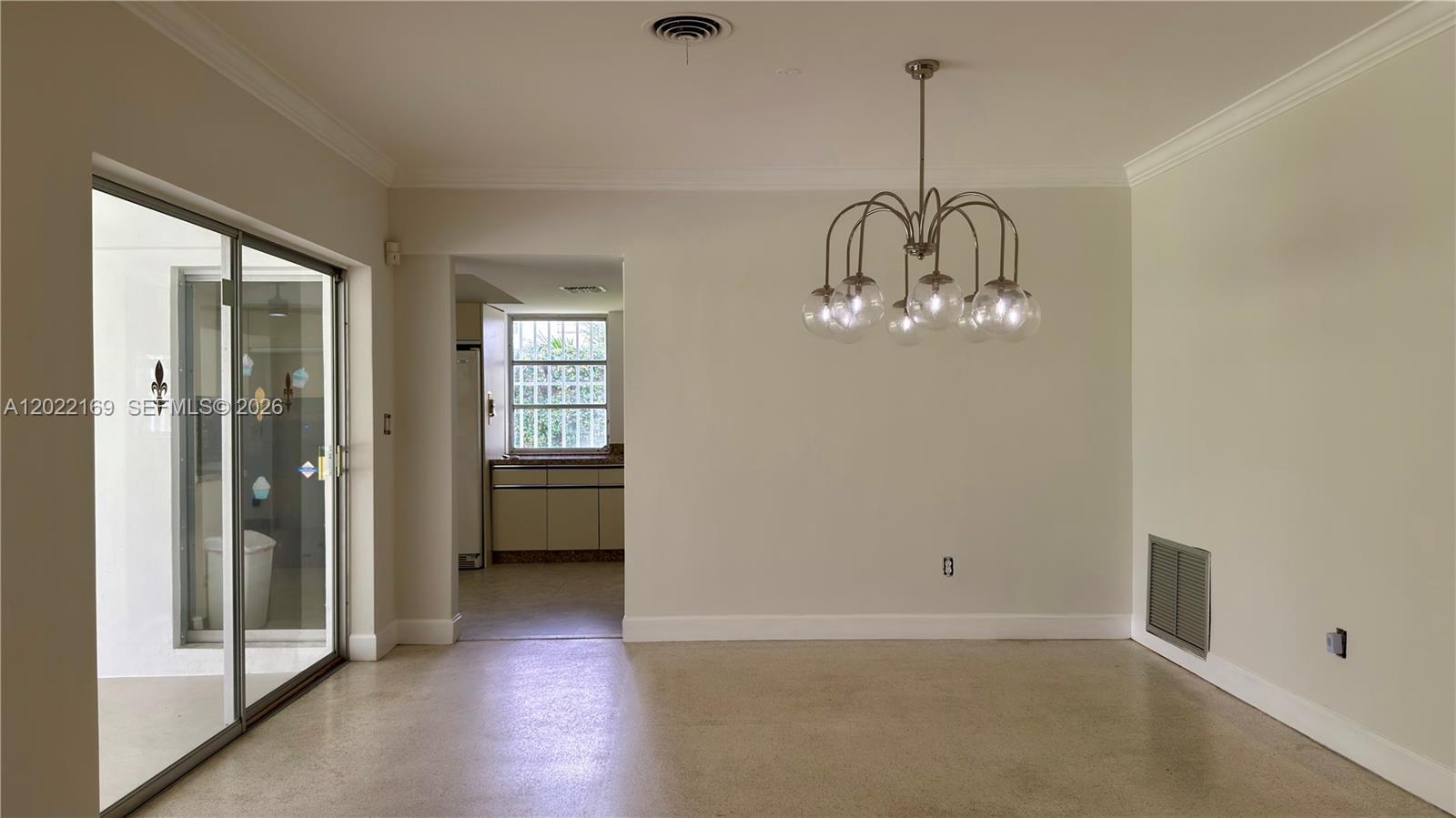 A dining area with a modern chandelier, sliding glass doors, and an adjacent kitchen — 7700 SW 52nd Ct, Miami FL 33143, MIAMI, FL