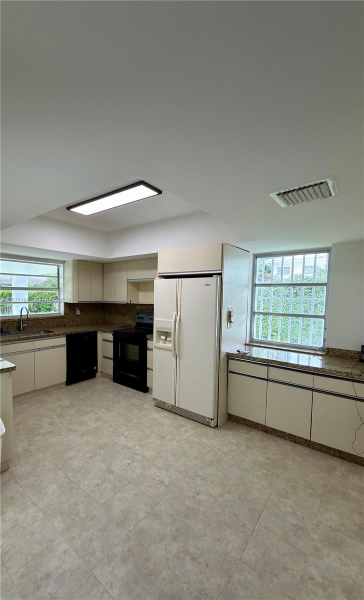 A kitchen features beige cabinets, granite countertops, a black stove, and a white refrigerator — 7700 SW 52nd Ct, Miami FL 33143, MIAMI, FL