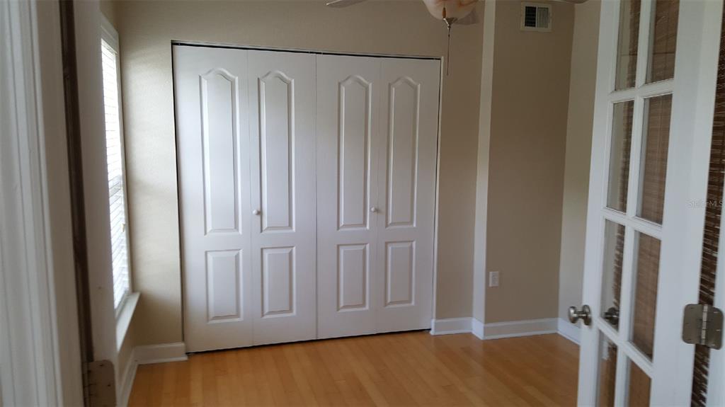 A room with hardwood floors, white bi-fold closet doors, and a glass-paneled door — 2035 DIXIE BELLE DRIVE UNIT 2035O, ORLANDO, FL