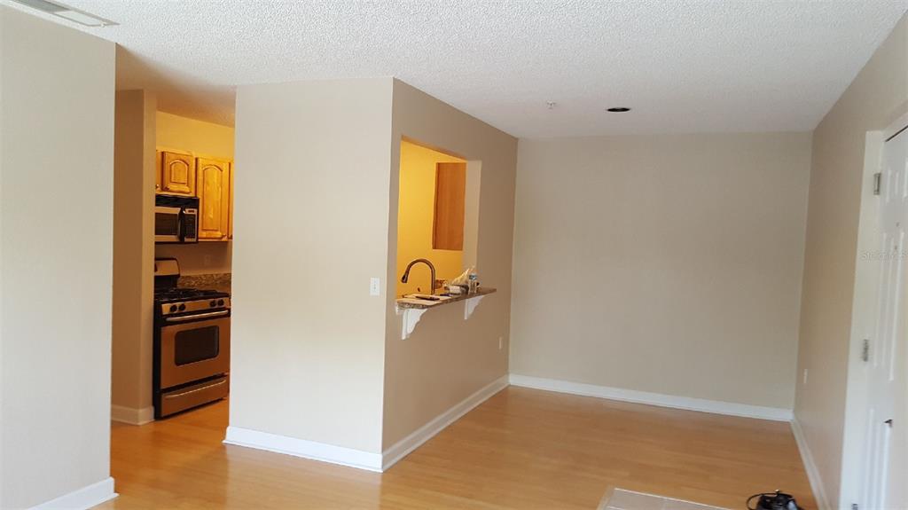 A view of a living area with light wood flooring and a kitchen pass-through window — 2035 DIXIE BELLE DRIVE UNIT 2035O, ORLANDO, FL