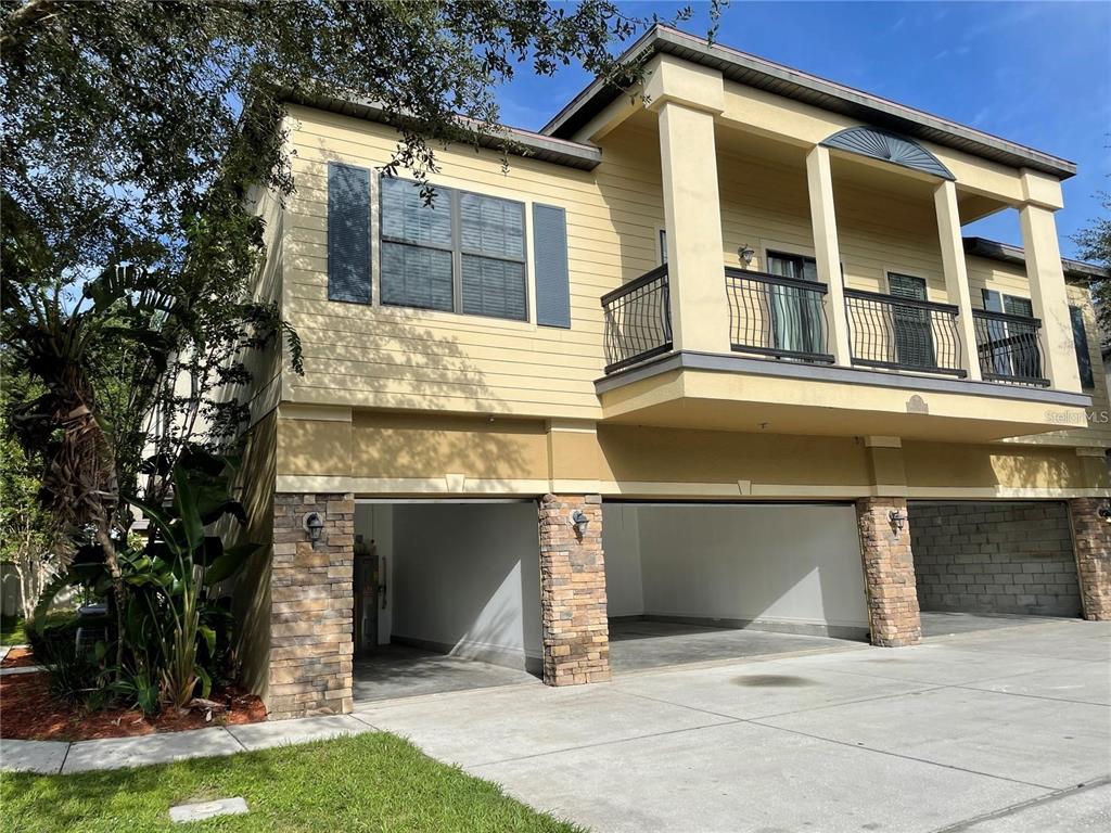 A two-story building exterior features a tan facade, stone-accented garage pillars, and an upper balcony — 3408 SENECA CLUB LOOP UNIT C, ORLANDO, FL