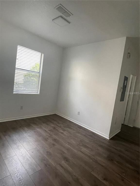 An empty room features white walls, wood-look flooring, a window with blinds, and a ceiling vent — 3408 SENECA CLUB LOOP UNIT C, ORLANDO, FL