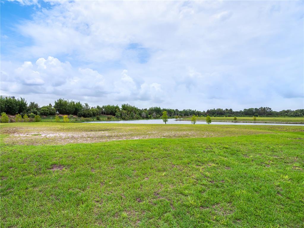 A grassy field leads to a small lake under a cloudy sky — LOT 32, CROMWELL RD, ORLANDO, FL