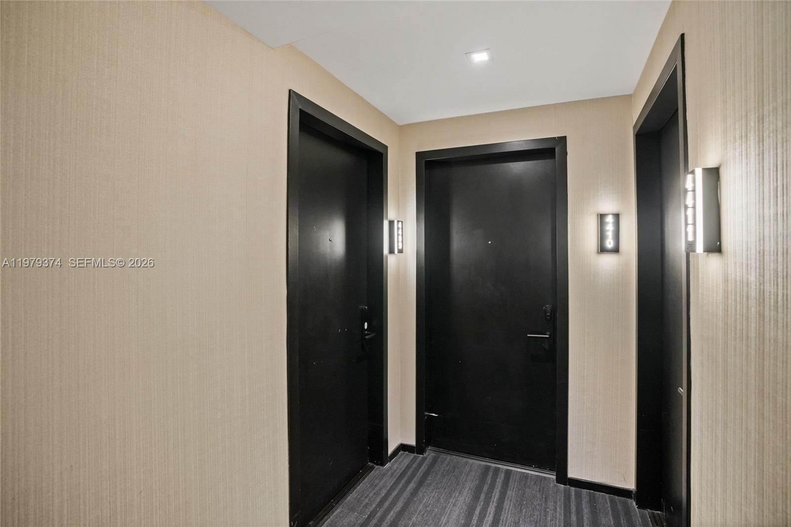 This hallway features beige textured wallpaper, dark doors, and modern wall-mounted light fixtures — 398 NE 5th St # 4410, Miami FL 33132, MIAMI, FL