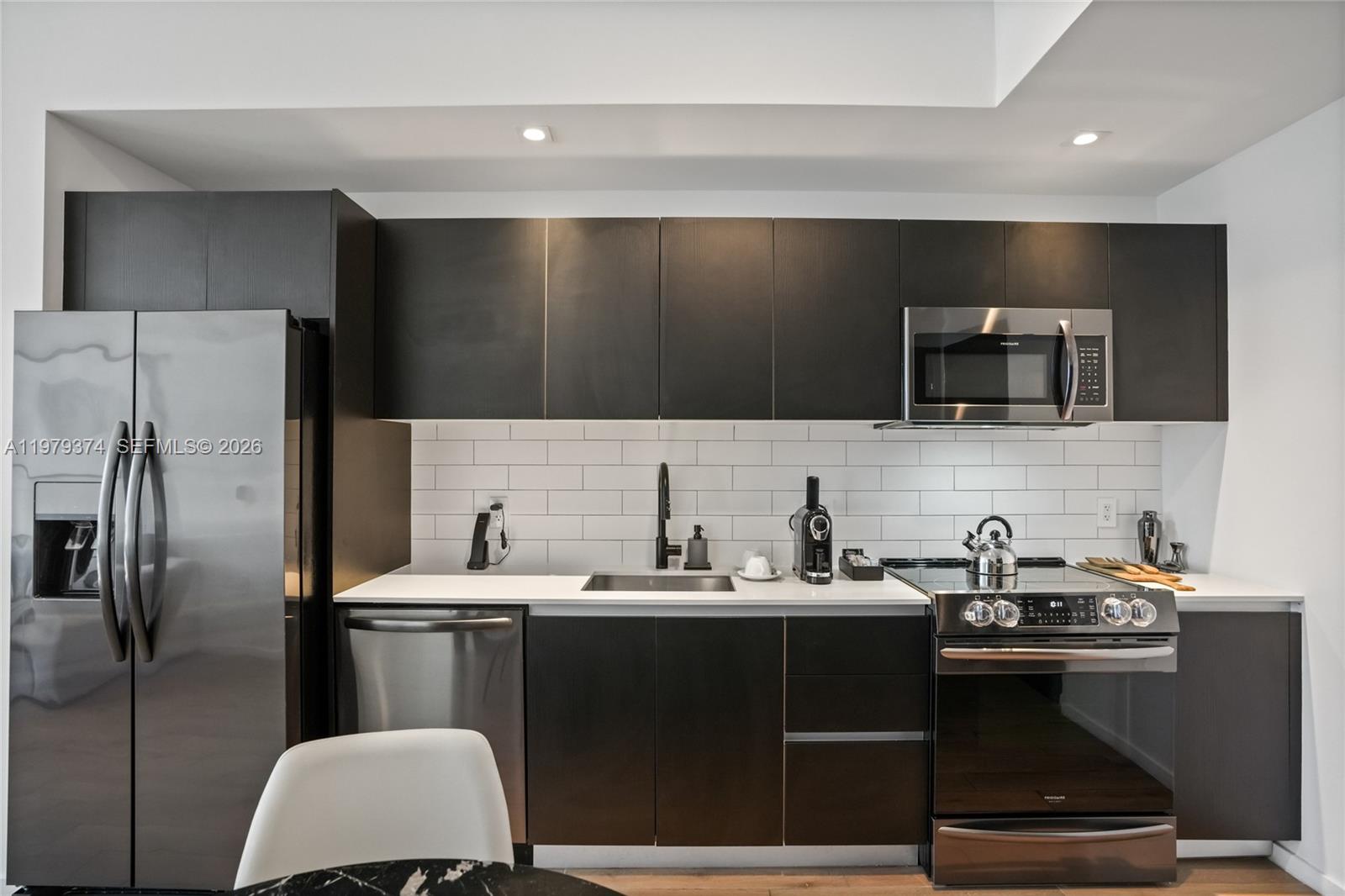 A modern kitchen features dark cabinetry, stainless steel appliances, and a white subway tile backsplash — 398 NE 5th St # 4410, Miami FL 33132, MIAMI, FL