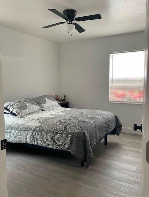 A bedroom features light gray flooring, a ceiling fan, and a bed with patterned bedding — 120 B STREET, LAKE WALES, FL
