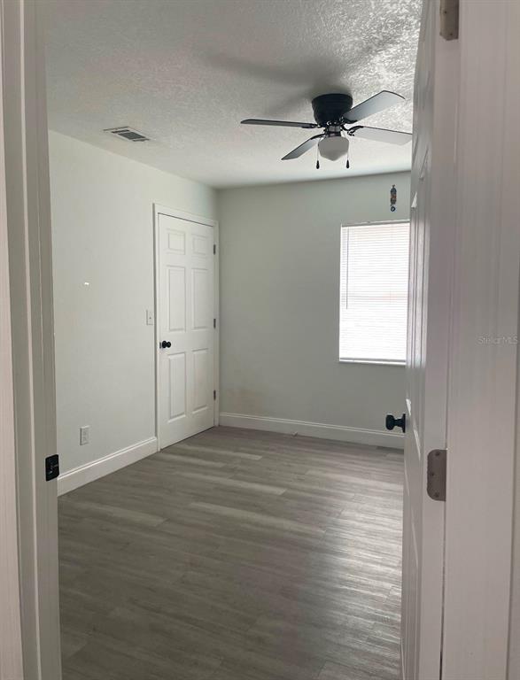 An empty bedroom features light gray wood-look flooring, white walls, and a ceiling fan — 120 B STREET, LAKE WALES, FL