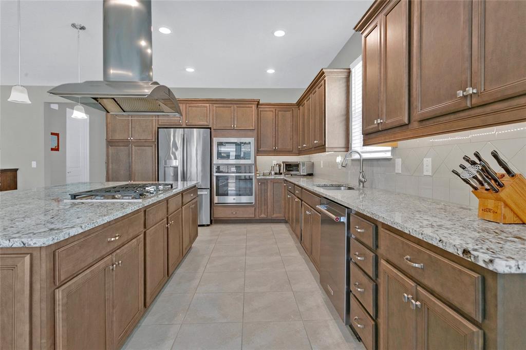 A kitchen features wood cabinets, granite countertops, stainless steel appliances, and a large center island — 4339 NW 56TH COURT, OCALA, FL