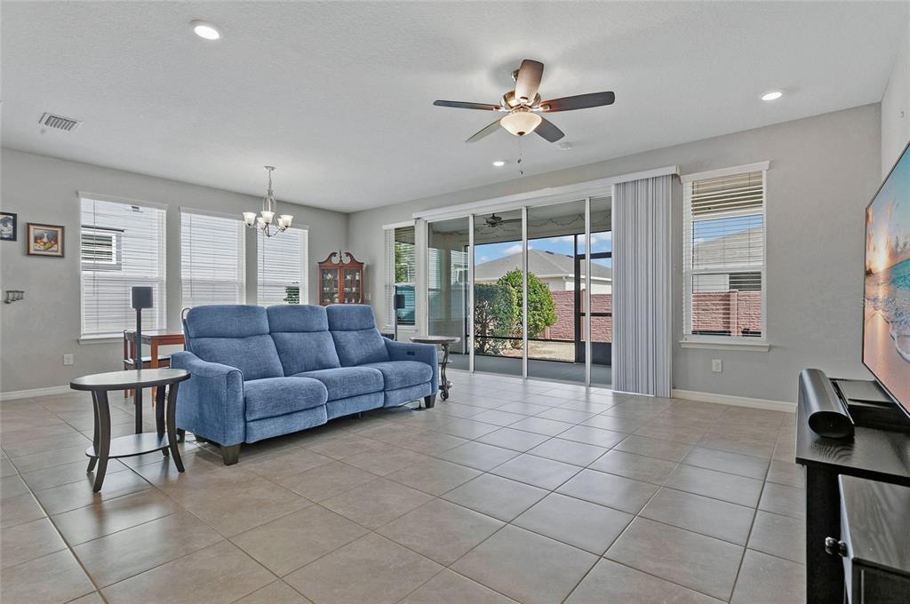 A living room features a blue sofa, tile flooring, a ceiling fan, and sliding glass doors — 4339 NW 56TH COURT, OCALA, FL