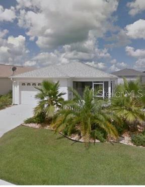 A white house with a driveway, a large palm tree, and a white picket fence — 1692 INDIGO AVENUE, THE VILLAGES, FL