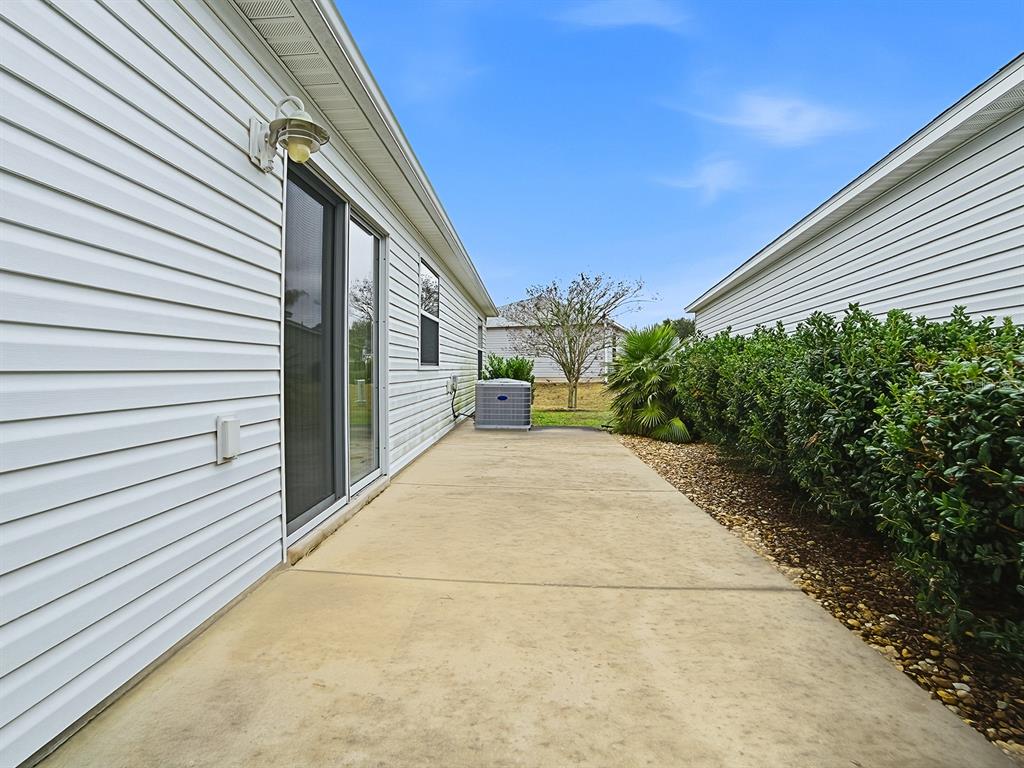 A black golf cart is parked inside a garage with concrete floors and insulated doors — 1692 INDIGO AVENUE, THE VILLAGES, FL